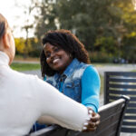 Two women siting outside, enjoying the fresh air, surrounded by natural beauty