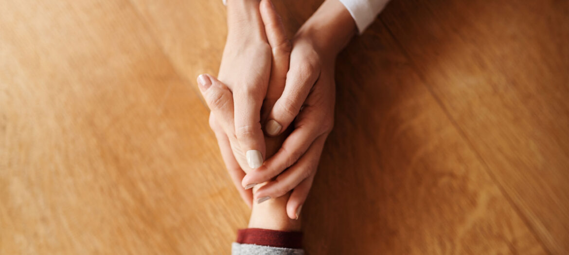 A photo of two people holding hands and offering support