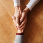 A photo of two people holding hands and offering support