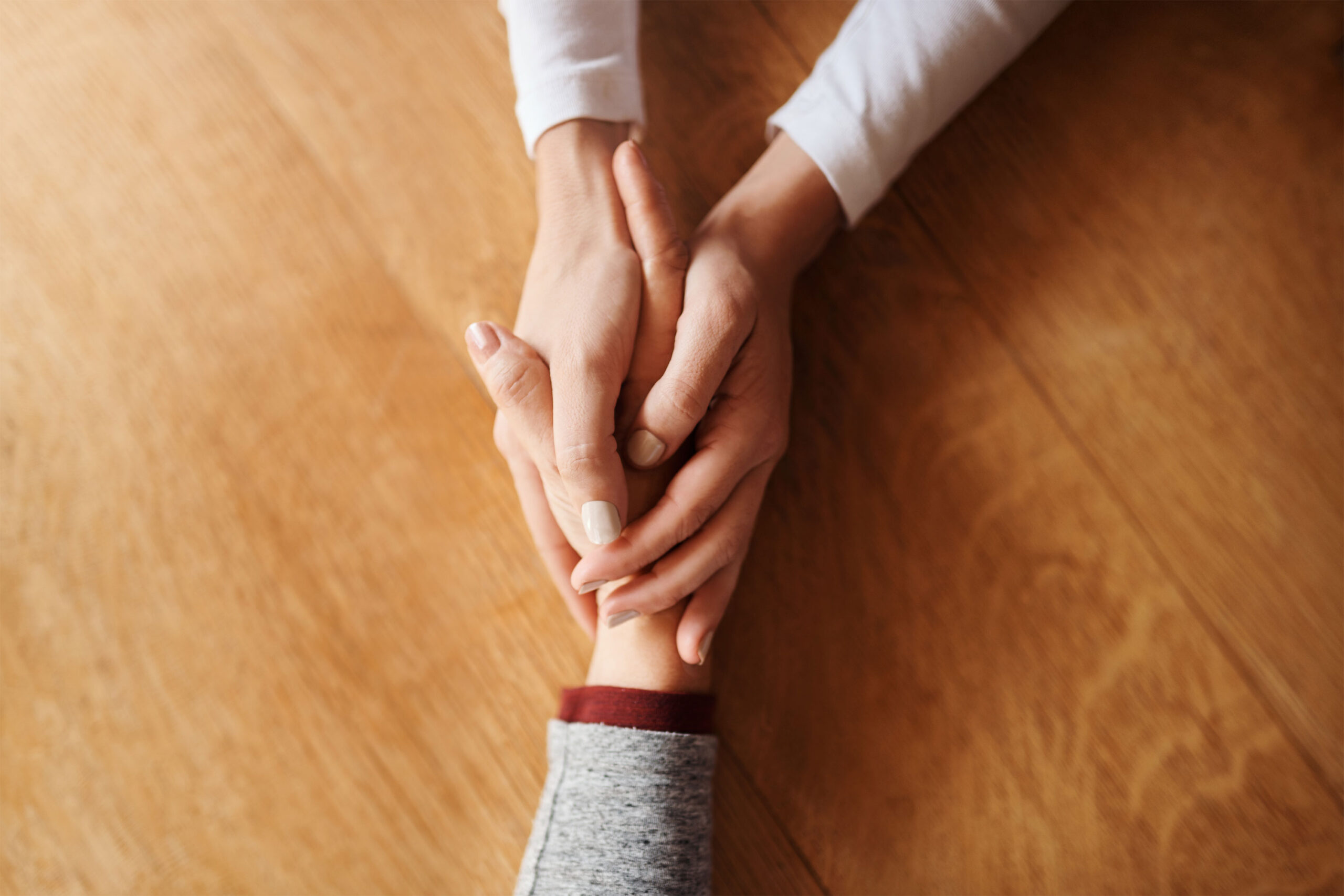 A photo of two people holding hands and offering support